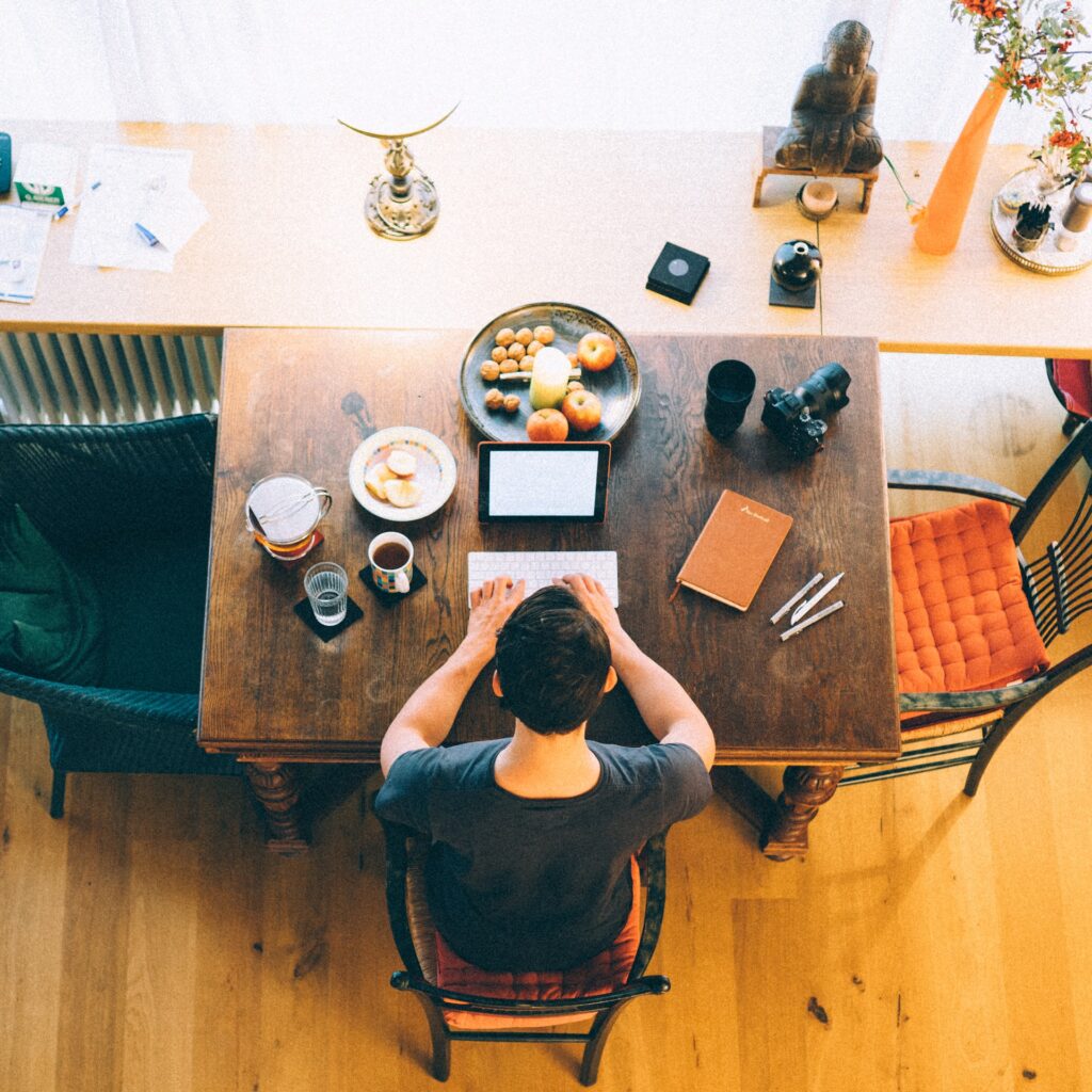 A man working on a laptop at a desk, with food on the desk.